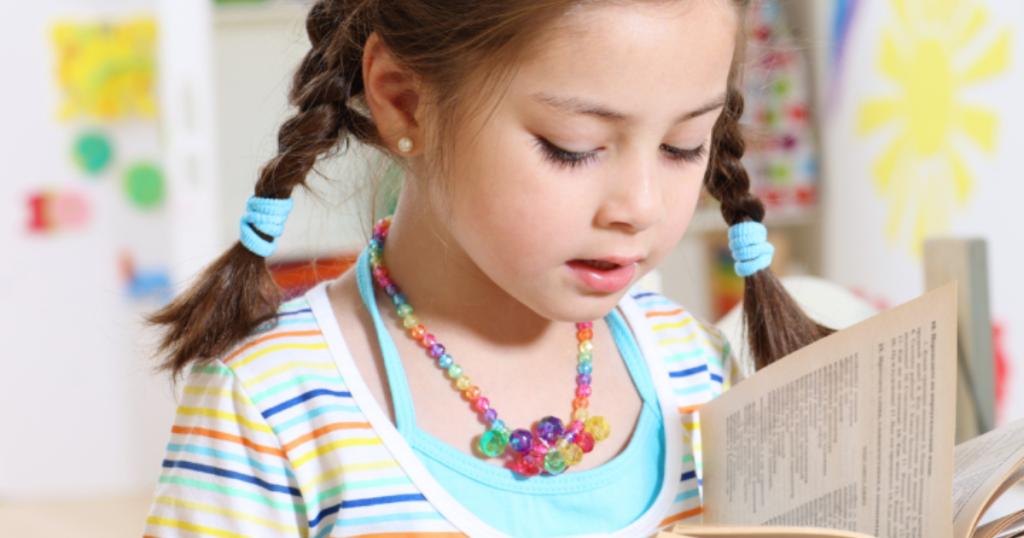 Young girl reading a book at an early learning center in Las Vegas supported by Grateful Hearts Inc. childcare scholarship program.